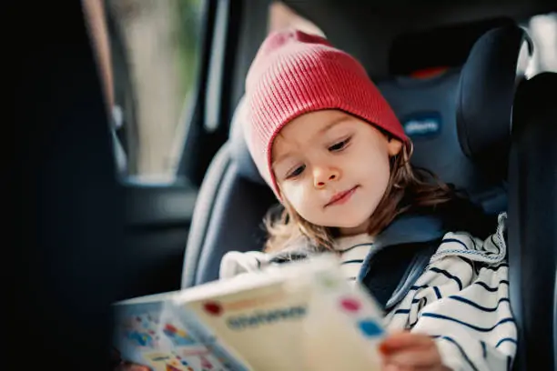 A child reading a book in a car seat