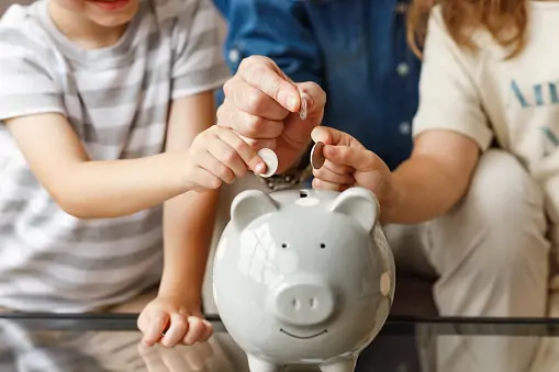 A parent and children putting money in a piggy bank